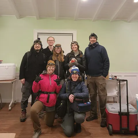 Seven lab members in winter hats and head torches, ready to sample cold-stunned lizards before dawn during the February 2026 Miami cold snap