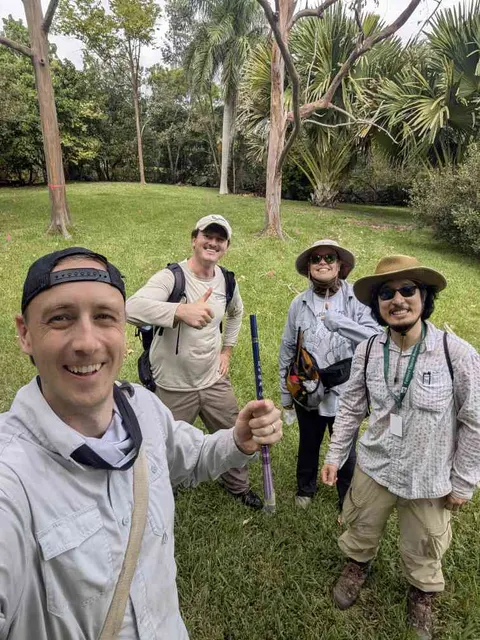 The fall 2024 field team on the lawn at Fairchild Tropical Botanic Garden, one holding a lizard-catching pole