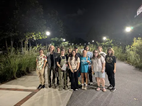 About a dozen lab members on a lamp-lit campus path at night