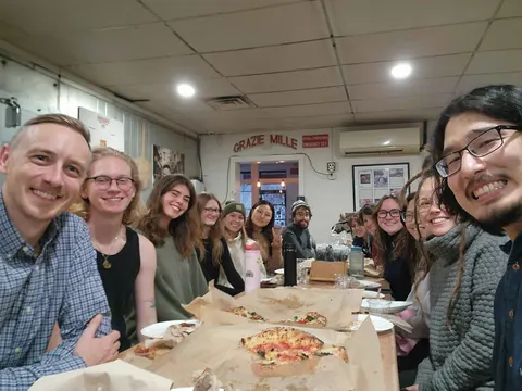 Lab members sharing pizza around a long restaurant table
