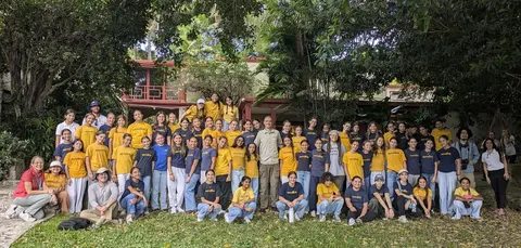 Stroud Lab members with a large group of Carrollton students in matching T-shirts, in a tropical garden